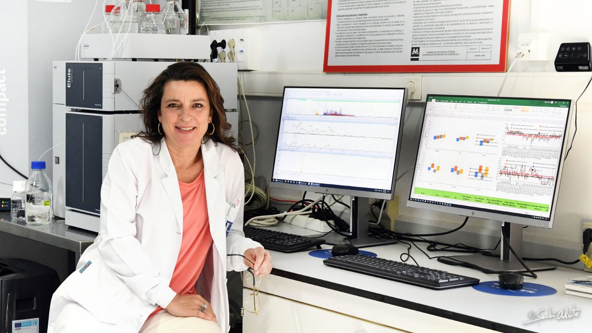 Marta Lores sitting in her lab with two computer screens.
